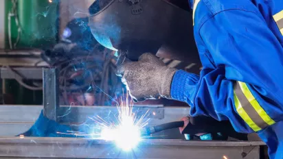 Un soldador usa guantes de protección para hacer su trabajo