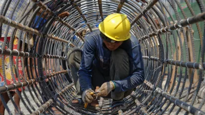 Man wearing hard hat while constructing metal structure.